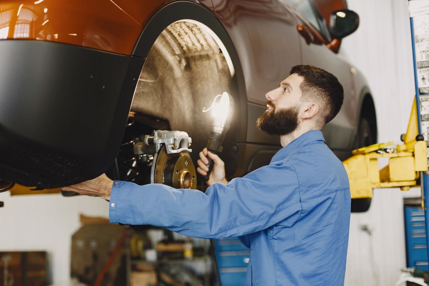 Mechanic inspecting an orange vehicle before purchase