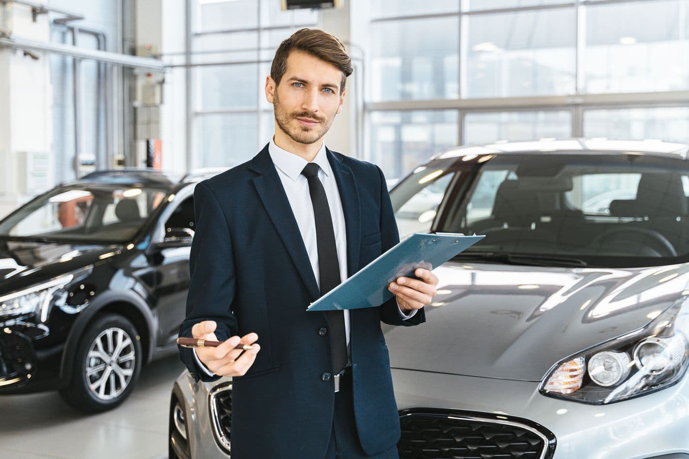 Professional car dealer holding a clipboard in a bright showroom
